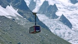 Close-up of a modern cable car pulley system in action against a mountain backdrop.