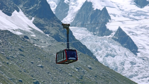 Close-up of a modern cable car pulley system in action against a mountain backdrop.