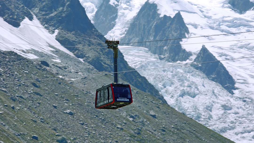 black and red cable car over snow covered mountain