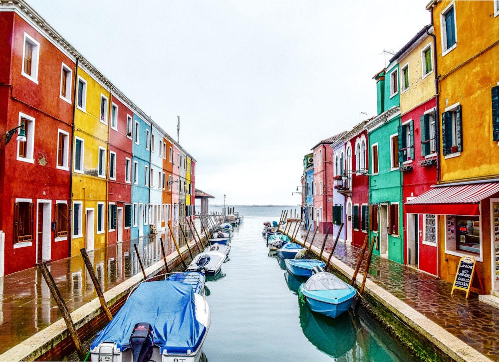 boats on river between buildings during daytime