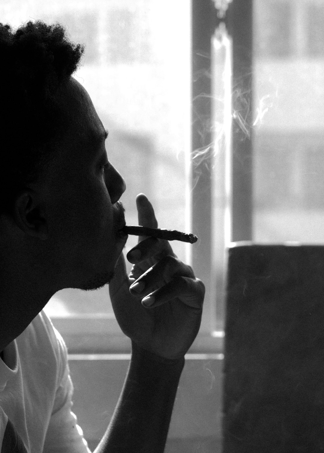 man smoking cigarette in grayscale photography