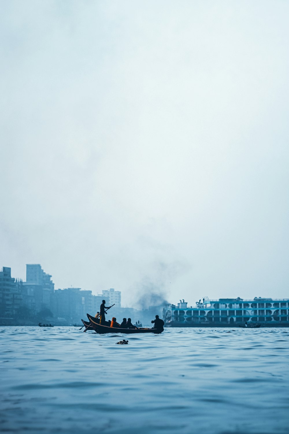 낮에 도시 건물 근처의 물 위에서 배를 타는 남자