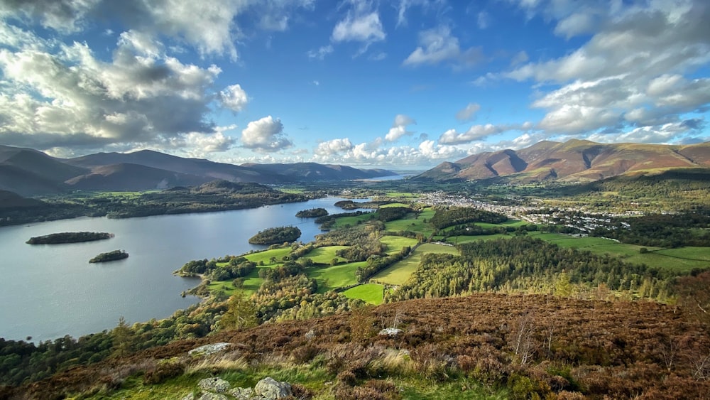 Campo de hierba verde cerca del lago bajo el cielo azul durante el día