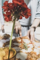 Close-up of a hand slicing a vegetable-topped pizza on a ceramic plate.