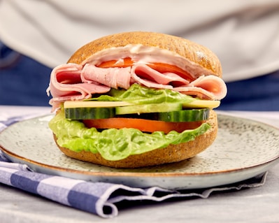 Close-up of a perfectly stacked classic ham and cheese sandwich with fresh lettuce and tomato.