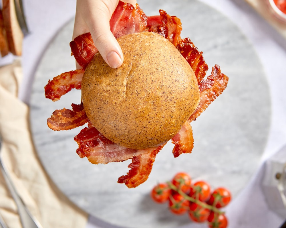 person holding brown bread with red sauce