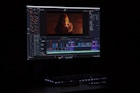 A computer monitor displays video editing software with a video track on the timeline. The screen shows various editing tools and a preview of a video featuring a person with red lighting.