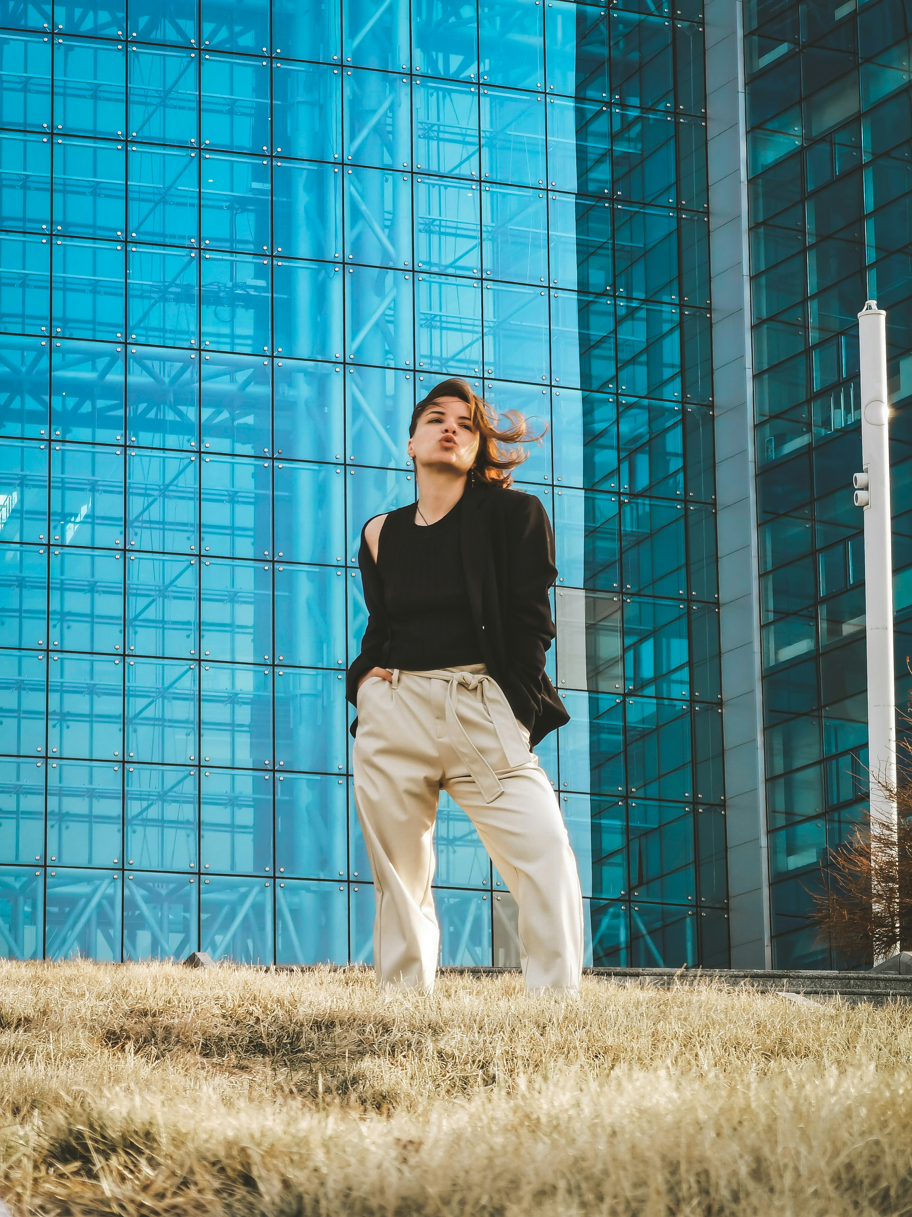 woman in black shirt and white pants standing beside blue wall