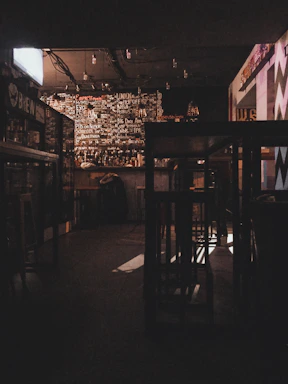 Dimly lit interior of the bar showing the industrial chic decor with matte black and amber gold accents.