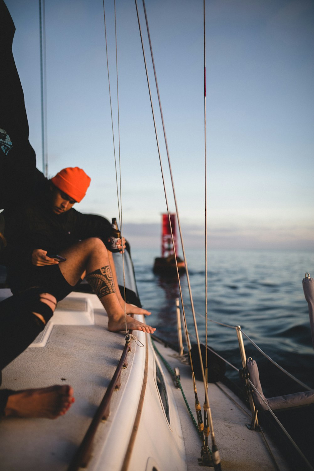 man in black t-shirt and orange cap sitting on boat during daytime