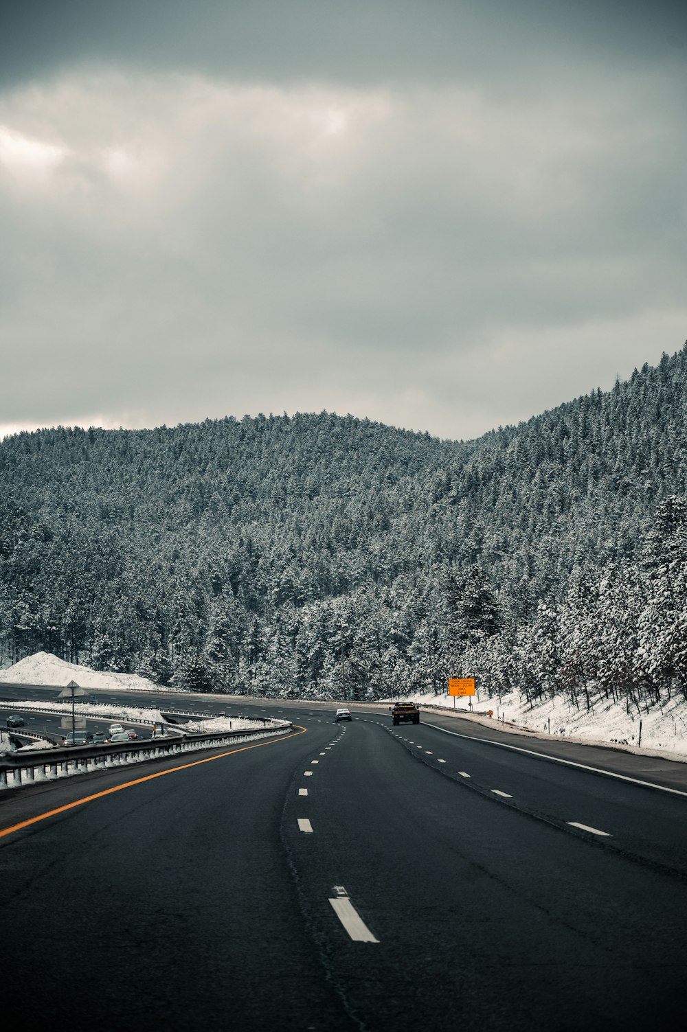 black asphalt road near green trees and mountain during daytime