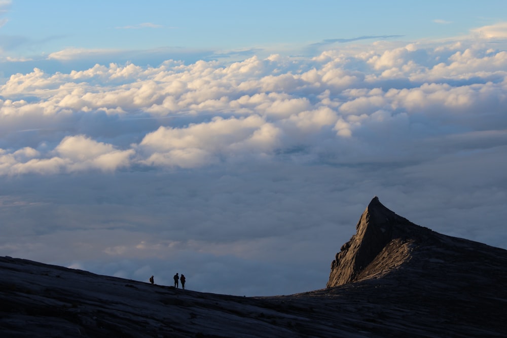 昼間、白い雲の下、山の上を歩く2人