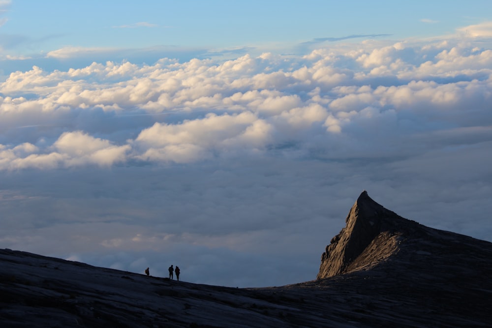 2 personas caminando en la montaña bajo nubes blancas durante el día