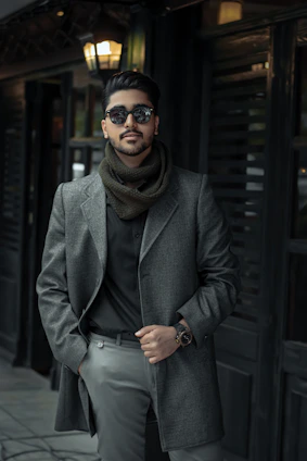 A stylish man wearing a warm jacket standing against a cool urban winter backdrop.