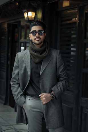 A sleek, minimalistic shot of a man in premium casual menswear, posed confidently against a soft gray backdrop with subtle gold accents.
