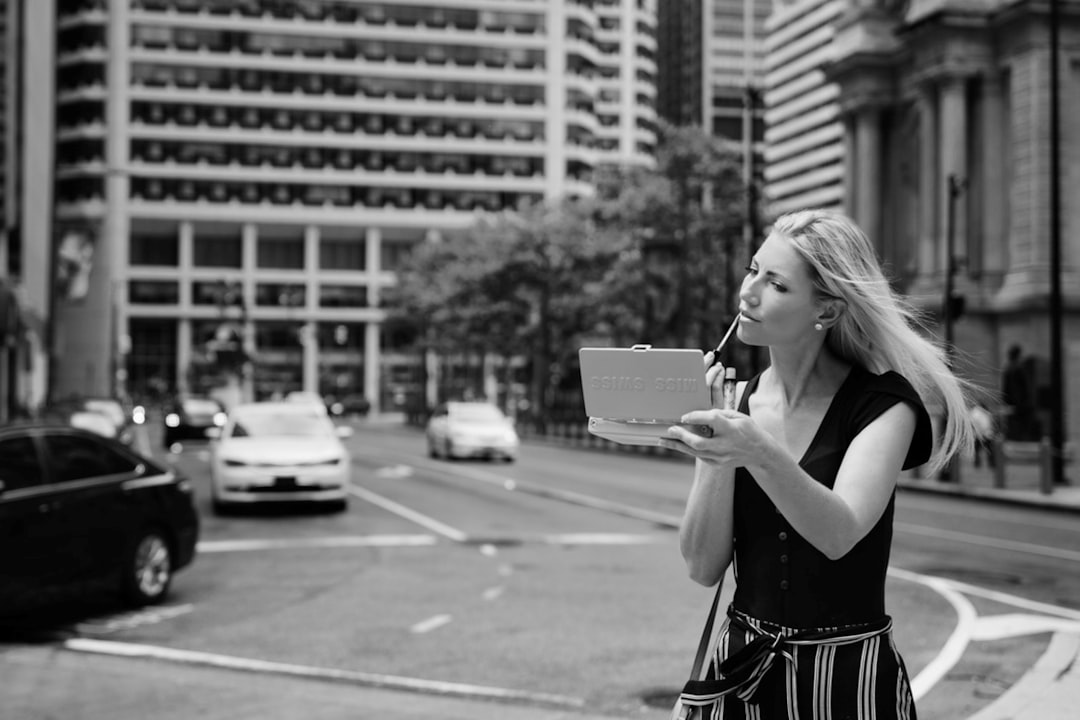 woman in black tank top holding book in grayscale photography