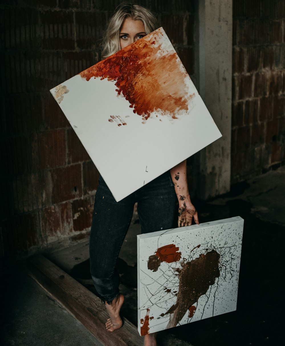 Persona sosteniendo pintura abstracta blanca y marrón