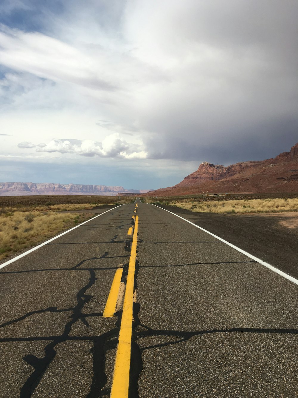 gray concrete road under white clouds during daytime