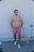 man in red shorts standing beside white wall