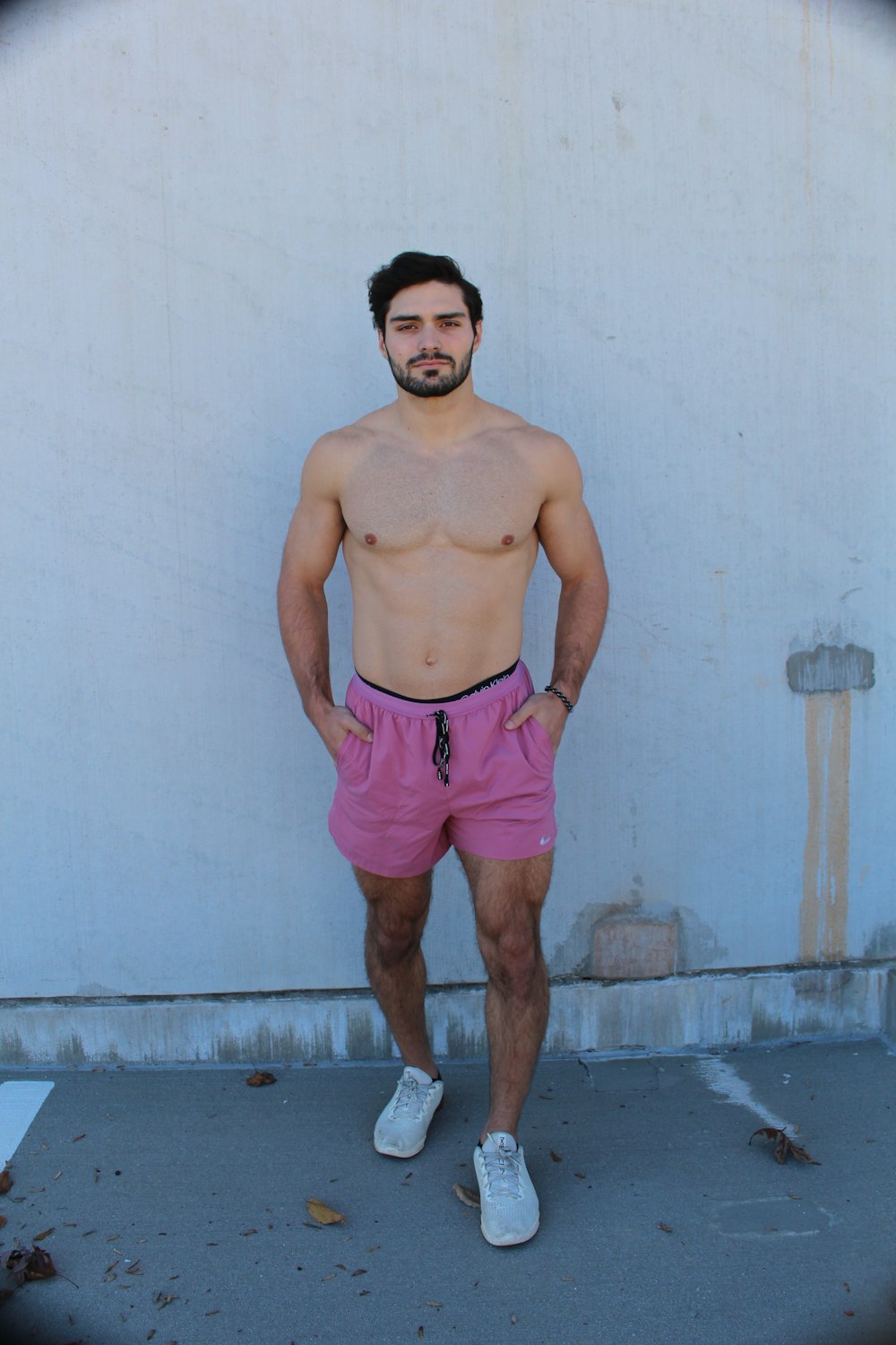 man in red shorts standing beside white wall