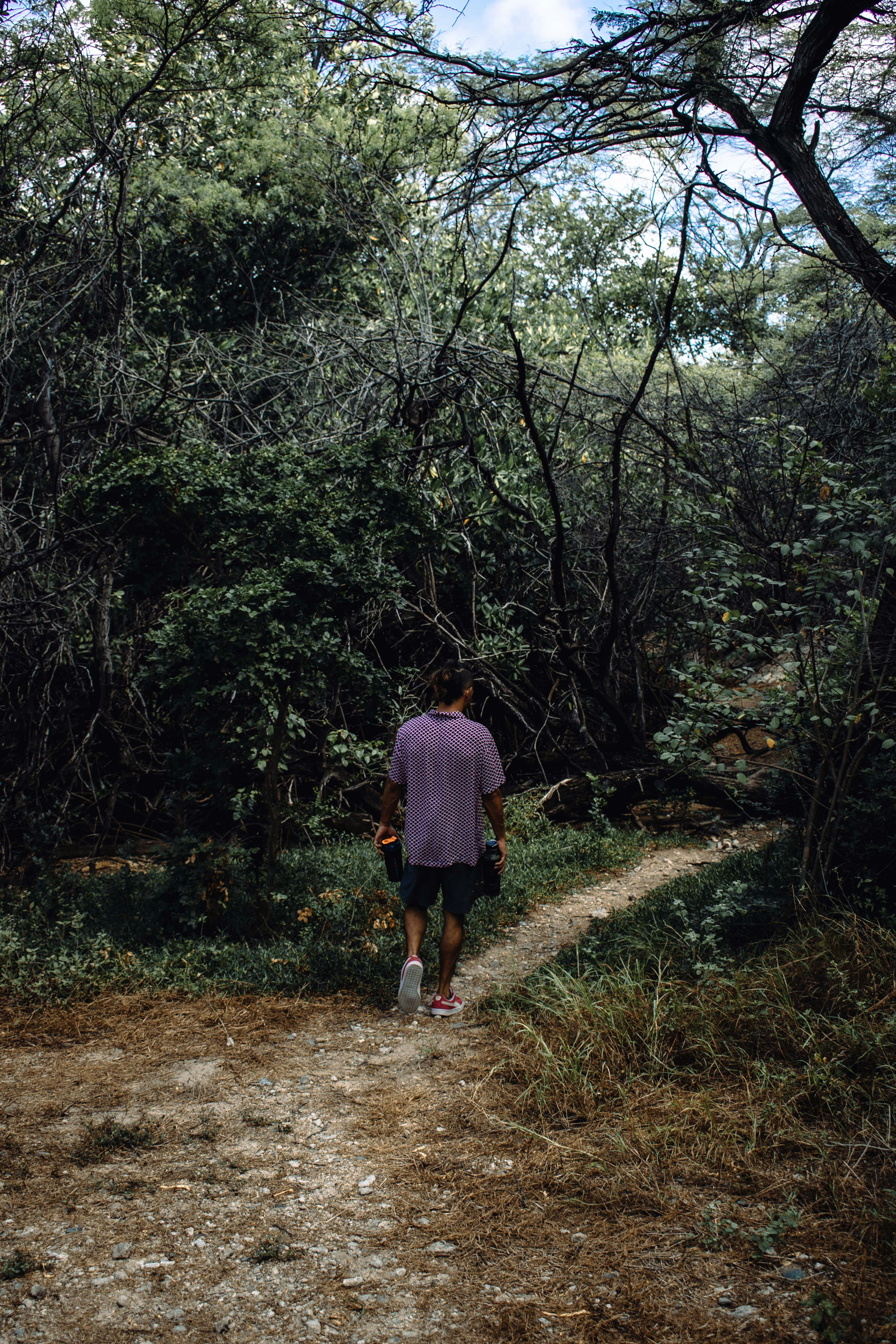 woman in pink jacket walking on dirt road