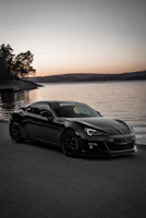 A sleek convertible car parked by a misty lake at dawn, with soft morning light reflecting on the water