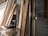 A collection of wooden planks leaning against a brick wall in a construction space. A power drill and other tools are placed on a makeshift wooden table nearby. The environment suggests an ongoing building or renovation project.