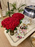A stylish red accent table with a vase of flowers on top.