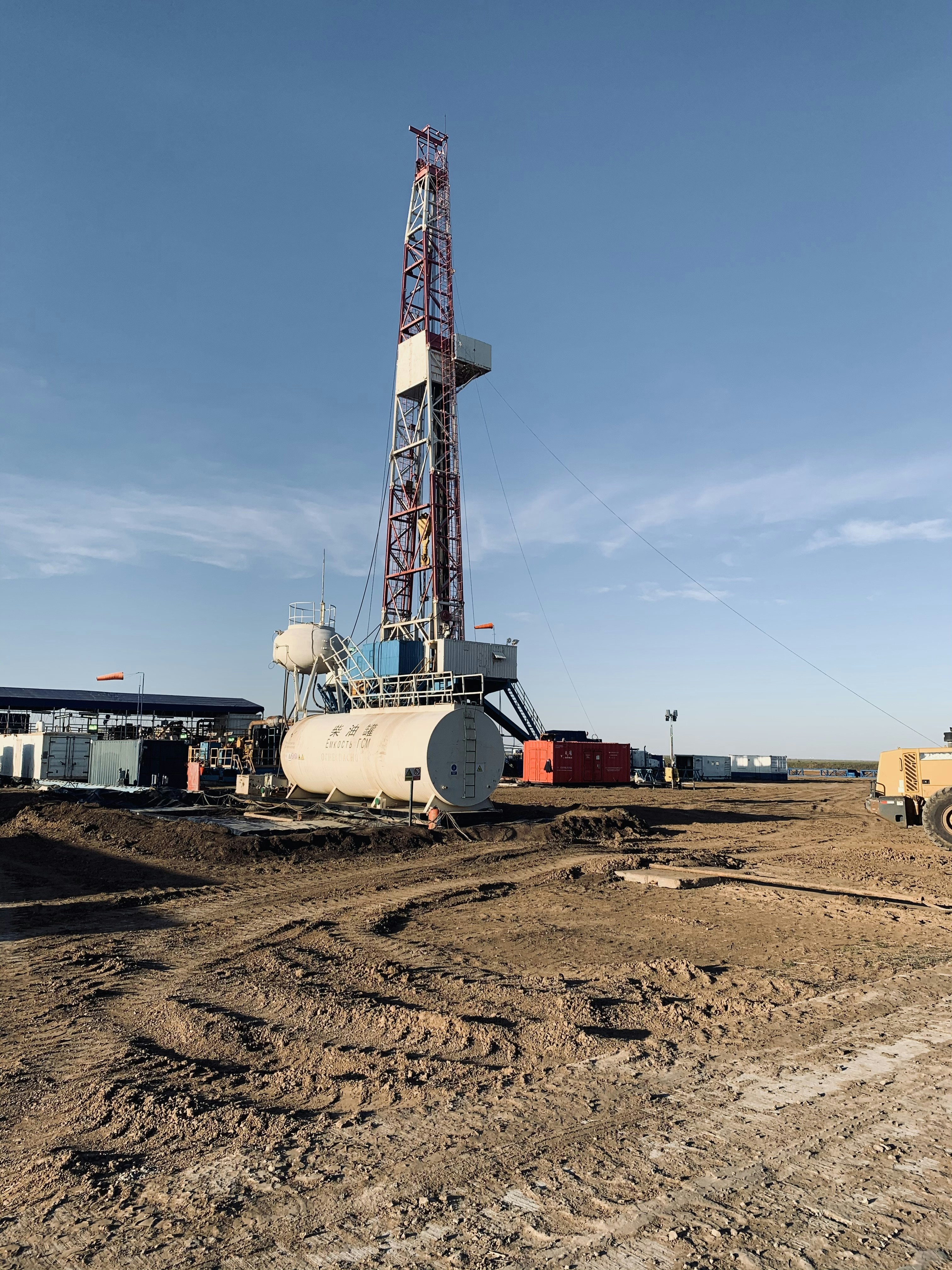 Heavy-duty borehole drilling rig operating on a dry open landscape under a blue sky