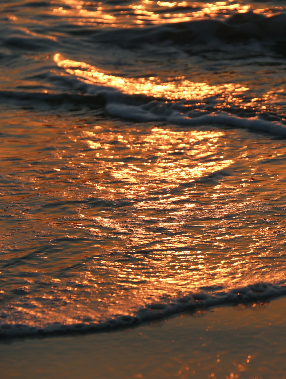 water waves on brown sand during daytime