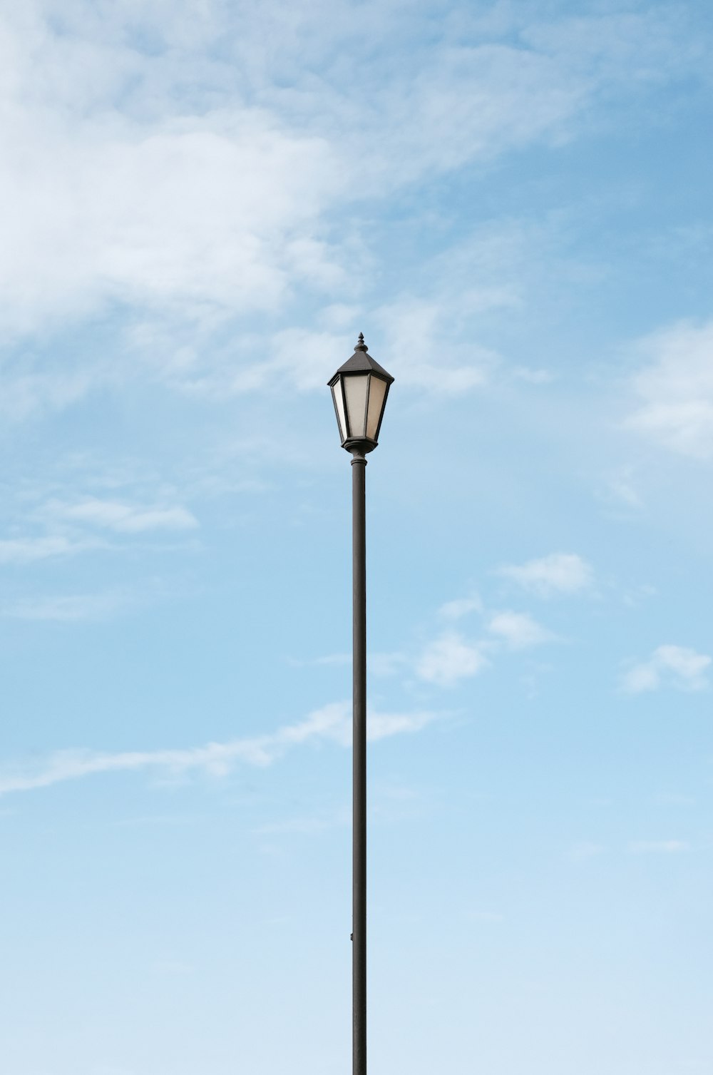 lâmpada de rua preta sob o céu azul durante o dia