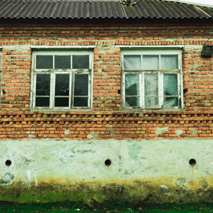 A close-up of a UK brick house wall showing a small crack near a window frame.