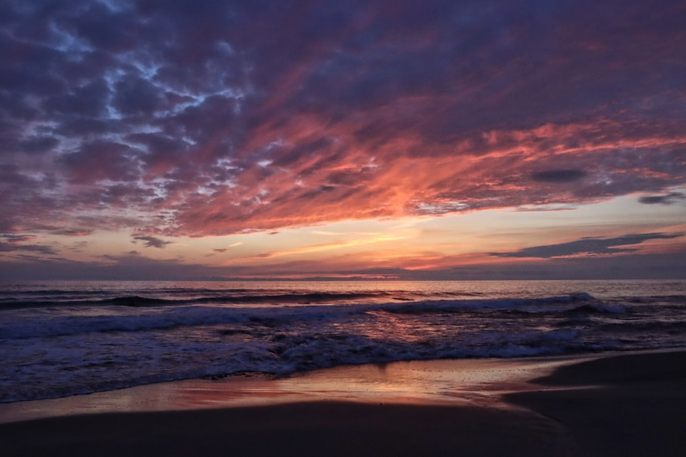 body of water under cloudy sky during sunset