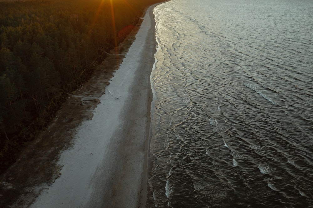 gray sand beside body of water during sunset