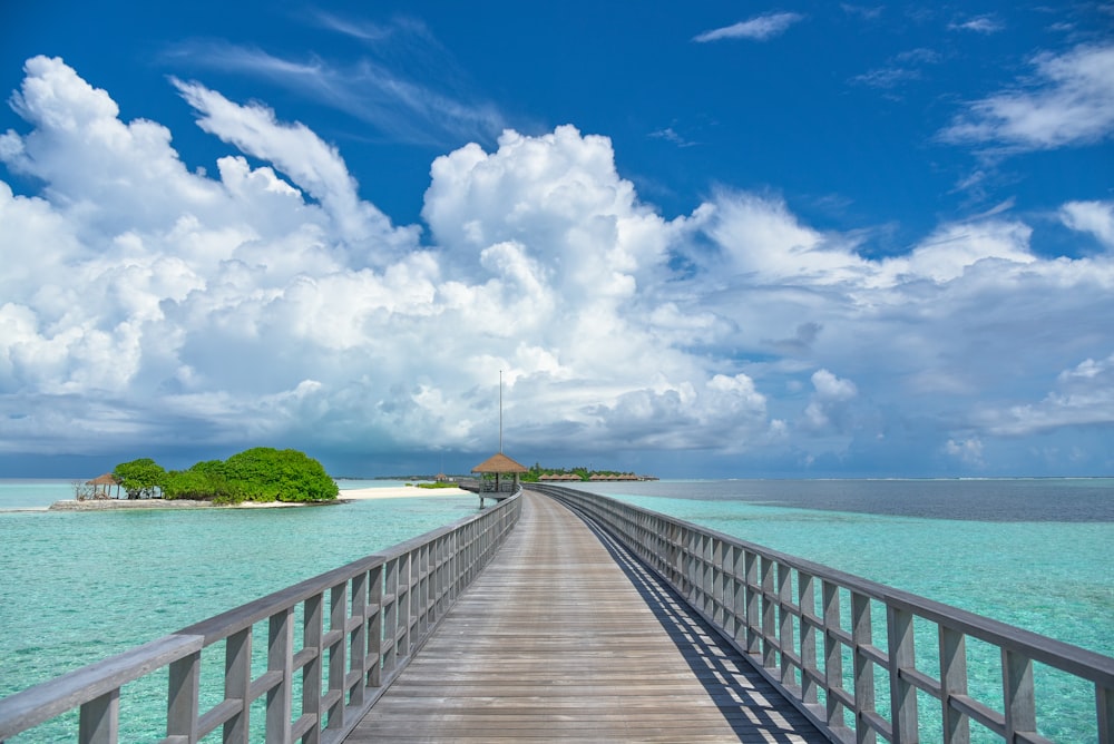 brown wooden dock on blue sea under blue and white cloudy sky during daytime