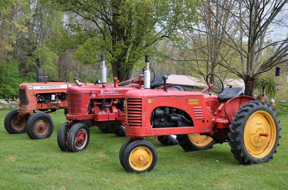 red tractor on green grass field near trees during daytime