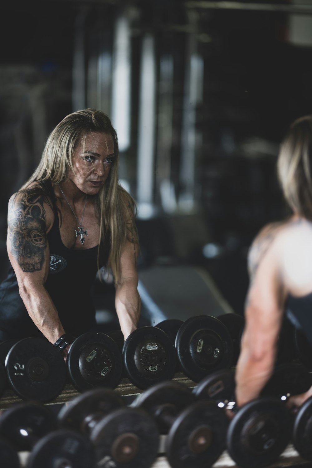 woman in black tank top holding black dumbbell