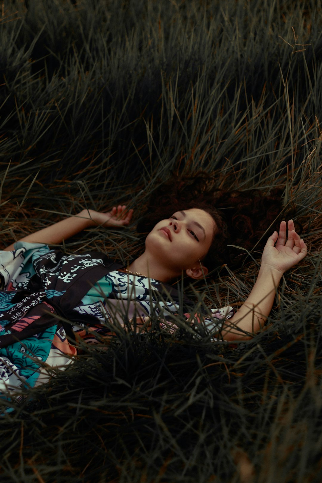 woman in blue white and red floral dress lying on brown grass field