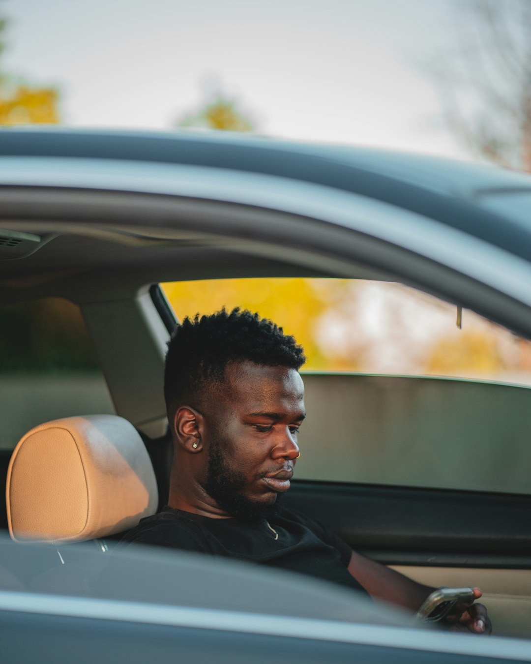 man in black leather jacket sitting inside car during daytime