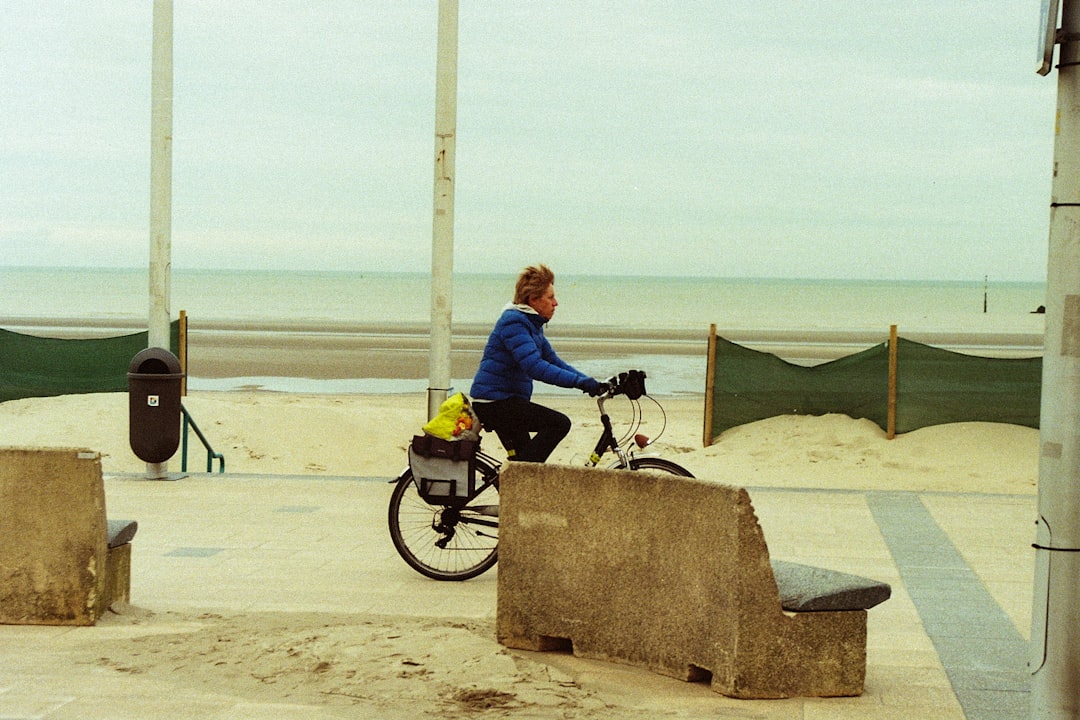 man in blue jacket riding on black motorcycle on beach during daytime