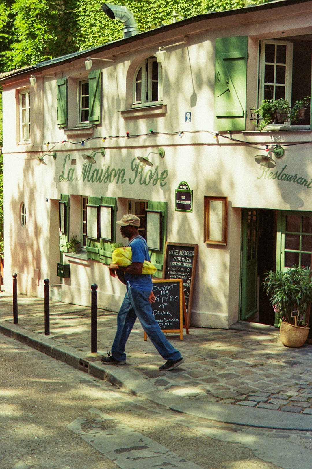 man in yellow shirt and blue denim jeans standing near green and white concrete building during