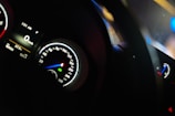 A dimly lit car dashboard showing various meters including a speedometer, tachometer, and a digital display. The speedometer reads zero, indicating the car is stationary. The time displayed is 1:51 AM, and the temperature is 22.5 degrees Celsius.