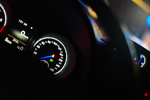 A dimly lit car dashboard showing various meters including a speedometer, tachometer, and a digital display. The speedometer reads zero, indicating the car is stationary. The time displayed is 1:51 AM, and the temperature is 22.5 degrees Celsius.