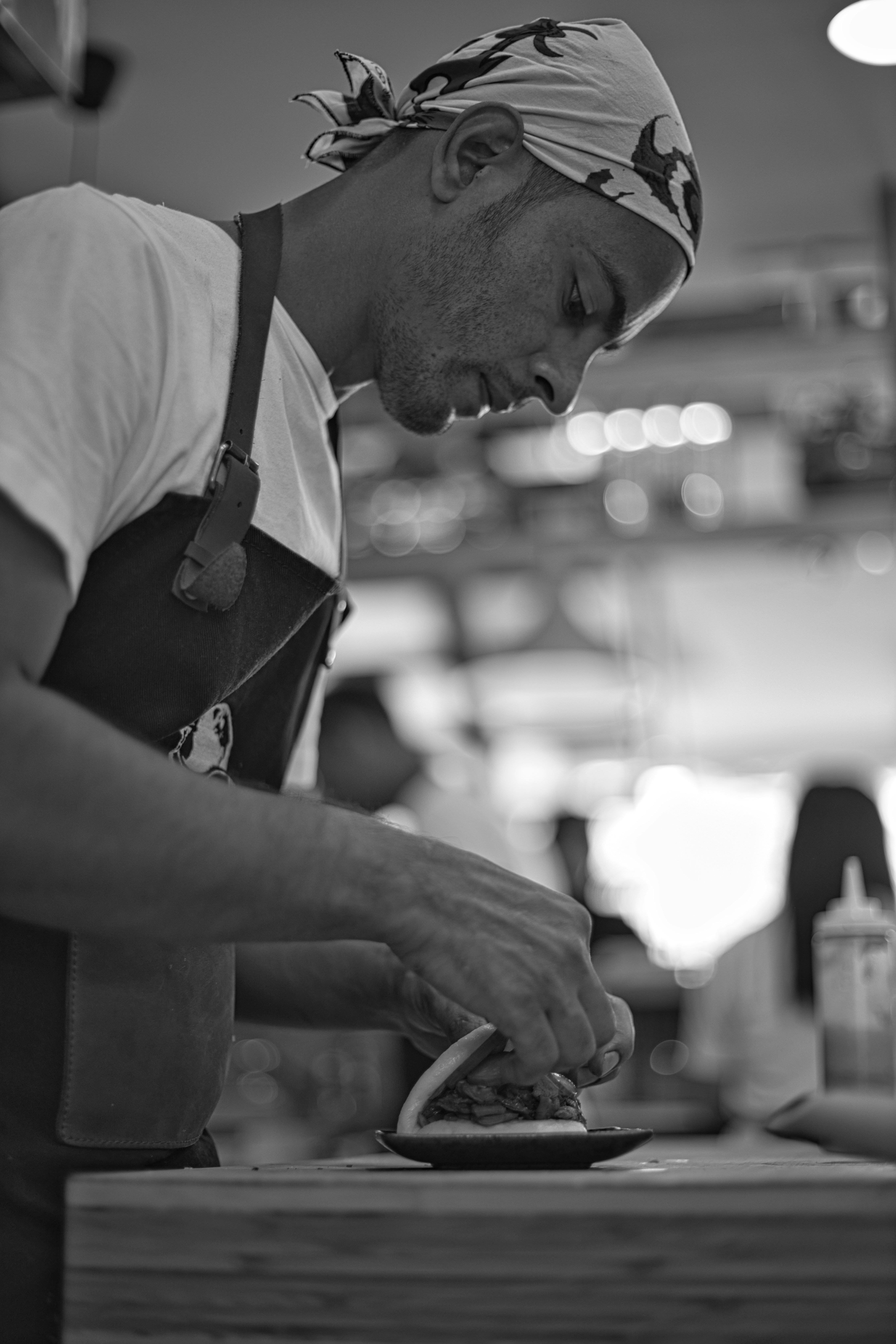 man in white t-shirt and black apron holding knife