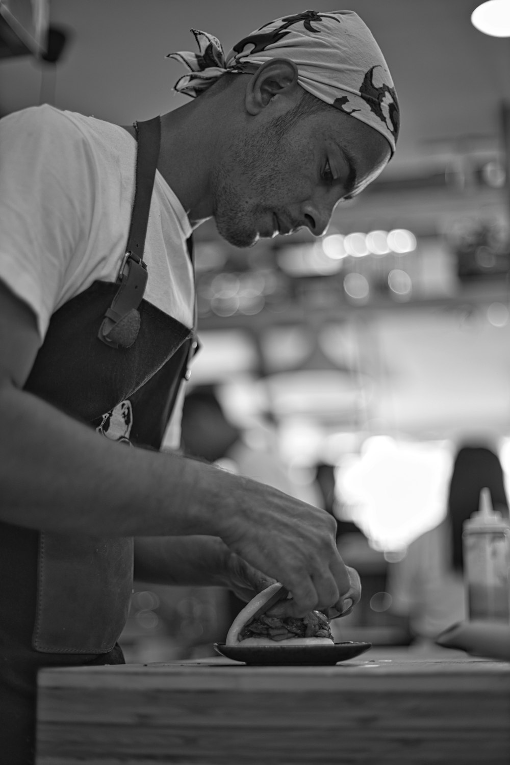 man in white t-shirt and black apron holding knife