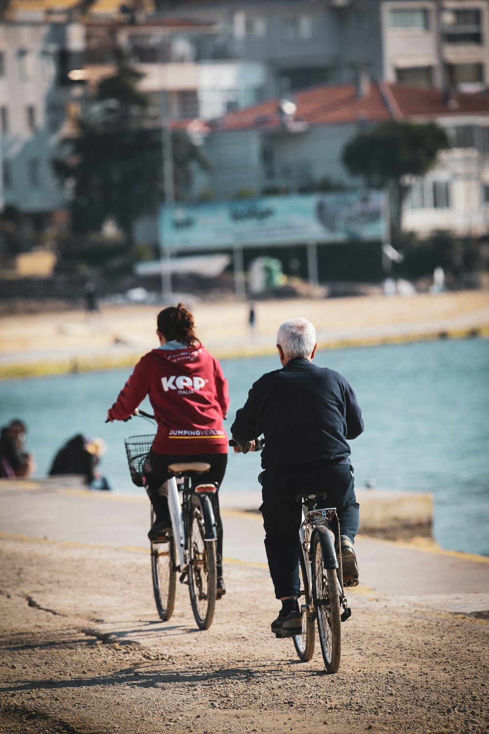 man in black jacket riding on bicycle near body of water during daytime