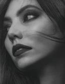 Side profile of a woman with bold, smoky eye makeup and perfectly styled hair