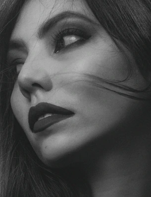 Side profile of a woman with bold, smoky eye makeup and perfectly styled hair