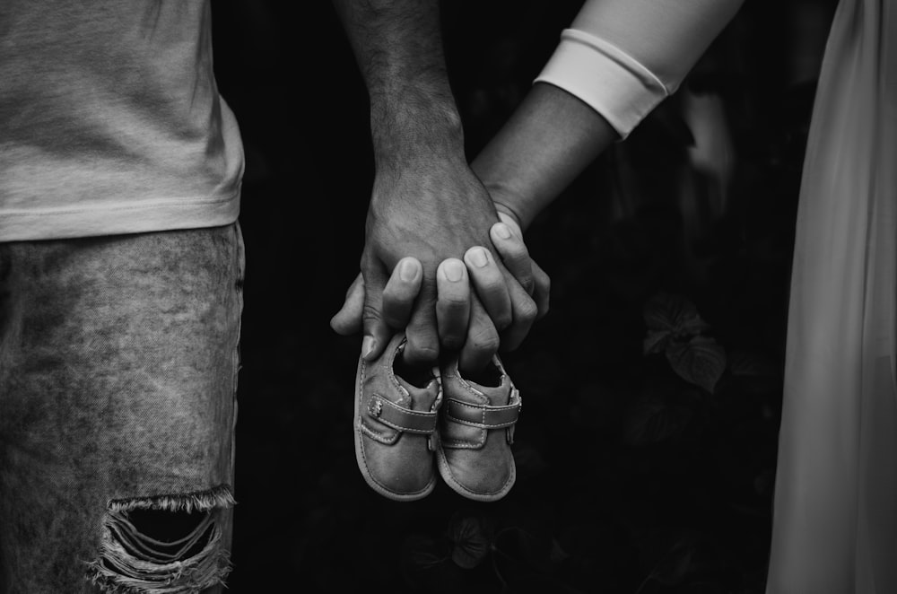 grayscale photo of person holding womans feet