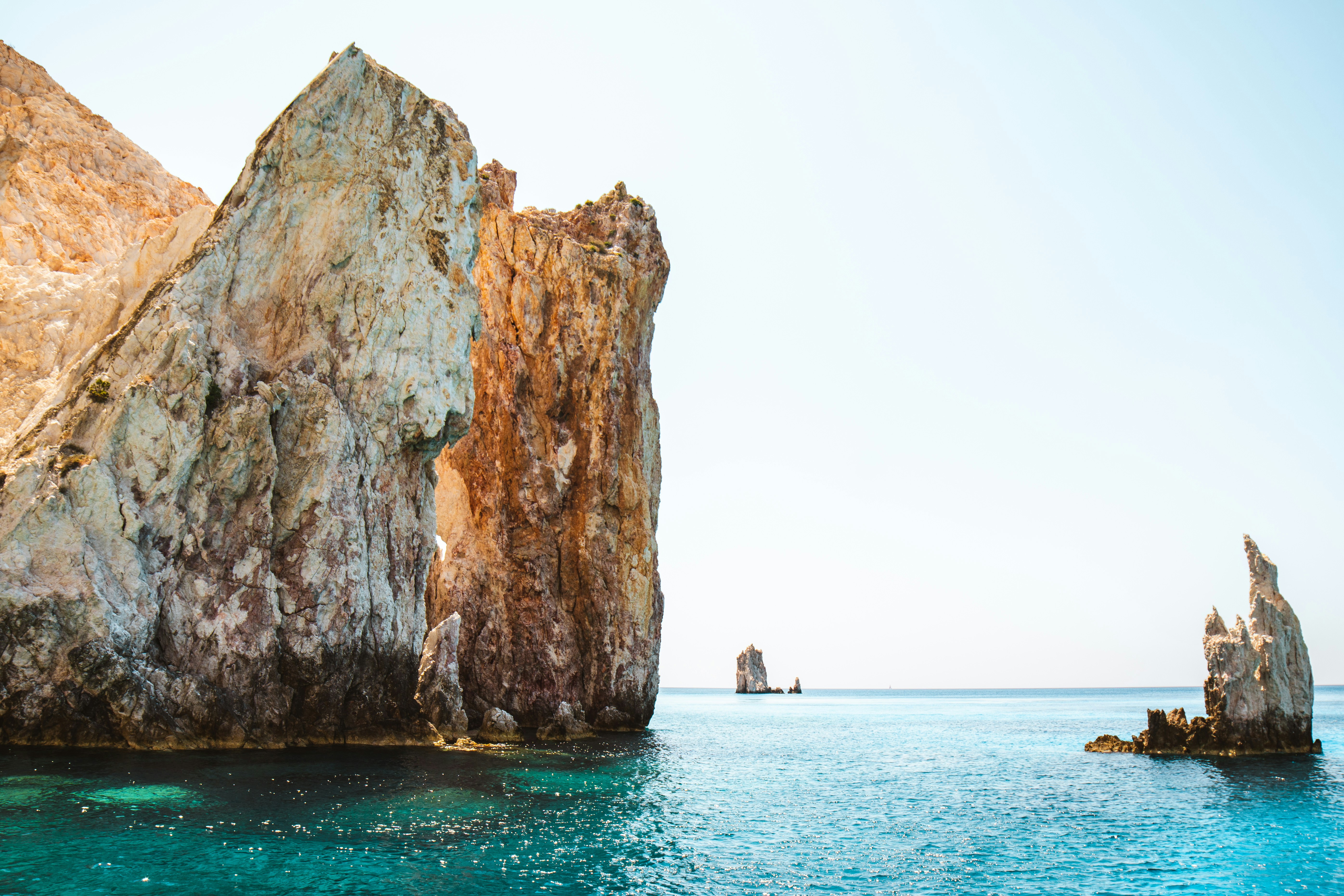 people in beach near brown rock formation during daytime